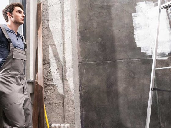 Ein Bauarbeiter steht in einem Raum der renoviert wird mit einer Leiter - Renovieren, Sanieren, Modernisieren