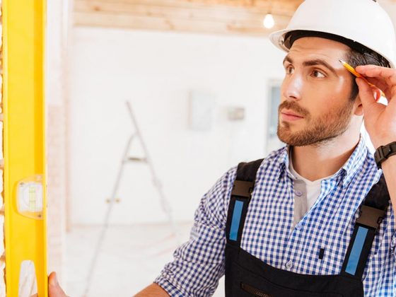 Ein Bauarbeiter mit Schutzhelm, Wasserwaage und Bleistift - Günstig bauen