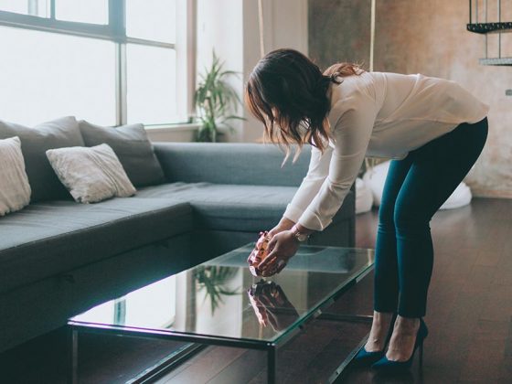 Eine Frau dekoriert das Wohnzimmer eines Hauses mit Home Staging, um die Immobilie auf eine Besichtigung mit Kaufinteressenten vorzubereiten | Home Staging